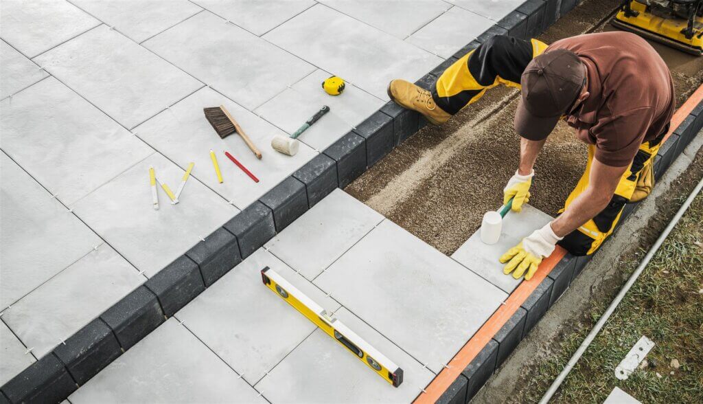 Crew member setting large-format porcelain pavers